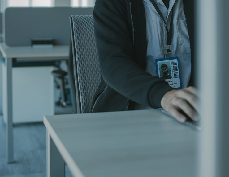 Person with ID badge sitting at a computer