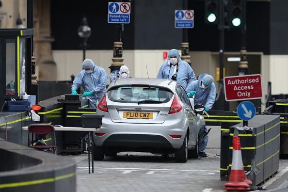 Police forensics officers work around a silver Ford Fiesta car that was driven into a barrier at the Houses of Parliament in central London