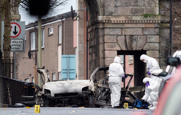 Police forensic officers inspect the aftermath of a suspected car bomb explosion in Derry, Northern Ireland