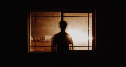 silhouette of a man looking out a window